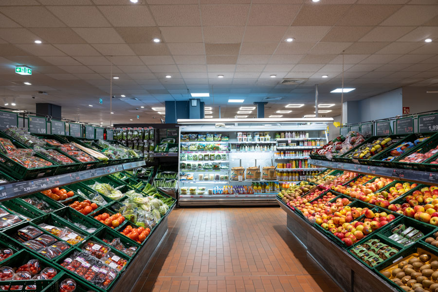 Obst- und Gemüseabteilung mit vollen Auslagen und Kühlwand im Hintergrund.