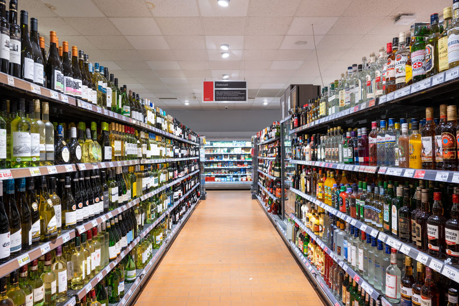 Langer Getränkegang mit Wein- und Spirituosenflaschen auf beiden Seiten.